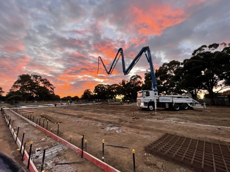 A.F. Concrete Pumping boom pump with the boom raised against a sunset sky